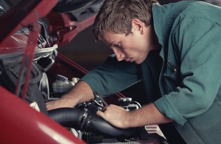 a technician working under the hood of a car