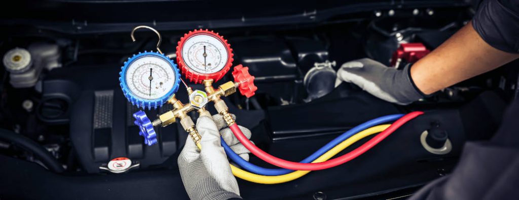 Hand of car mechanic technician use meter to check car air conditioner system heat problem and fix repairing and filling air refrigerant.
