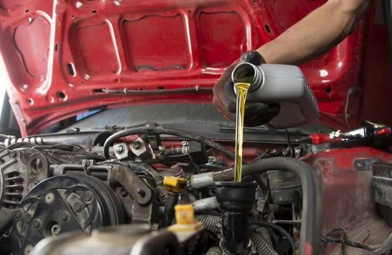 Oil being poured from a jar into an orifice of a vehicle's engine