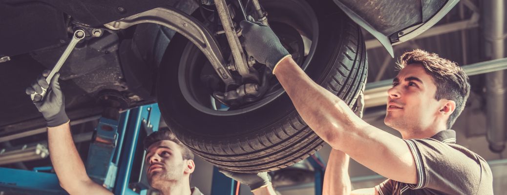 Two mechanics working on a vehicle at a service center