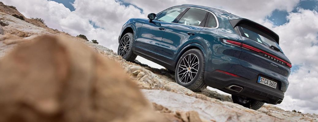 One green color 2023 Porsche Cayenne is running on the rocky road.