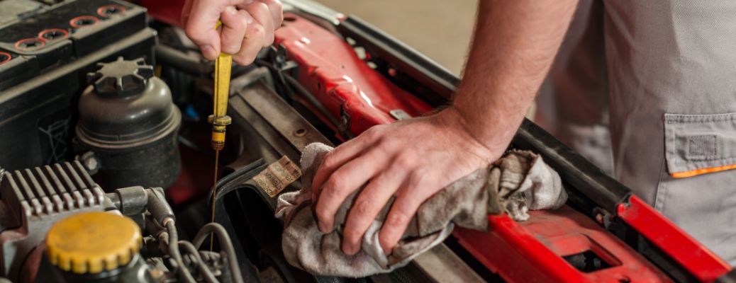 Technician using a dipstick to check oil levels