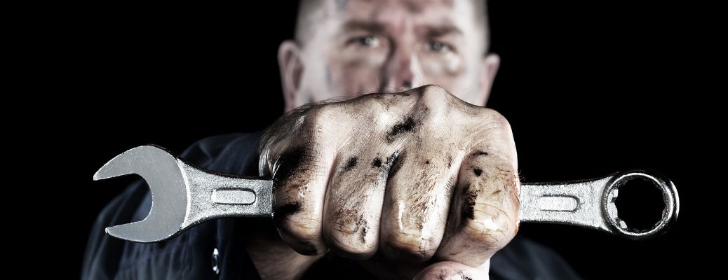 Technician with grime on his hand showing a tool to the camera