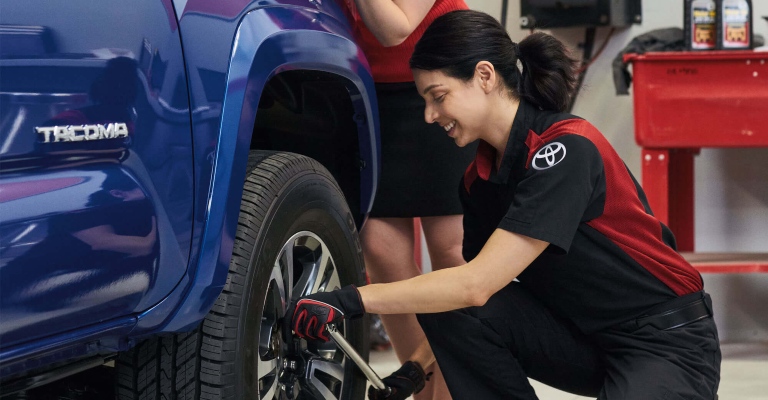 Woman working on the tire of a Tacoma