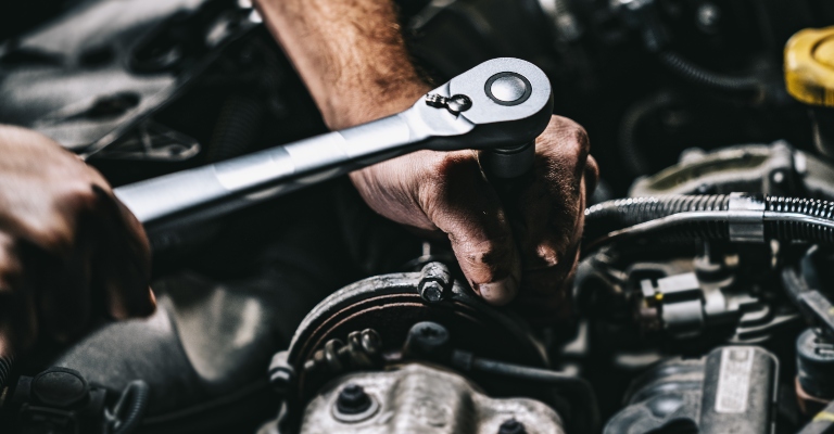 mechanic using a wrench on an engine