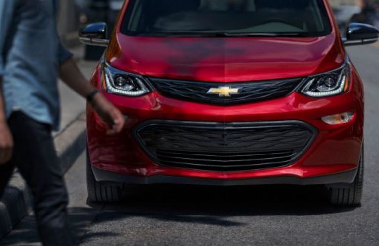Man crossing the road with a 2020 Chevy Bolt EV Red on the background