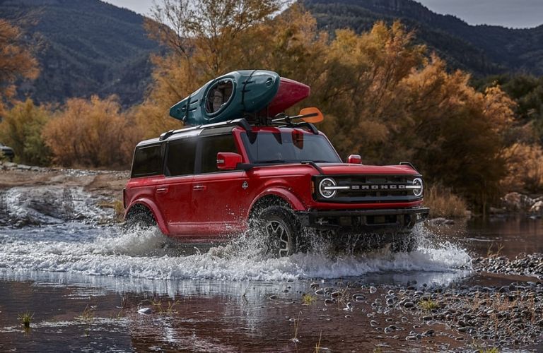 Red 2024 Ford Bronco in a River with Rooftop Kayak Carrier