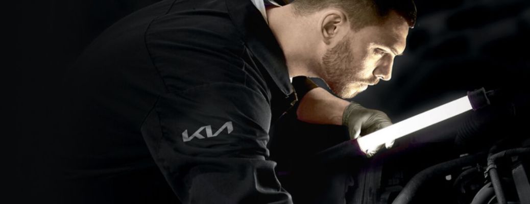 a technician working under the hood of a Kia