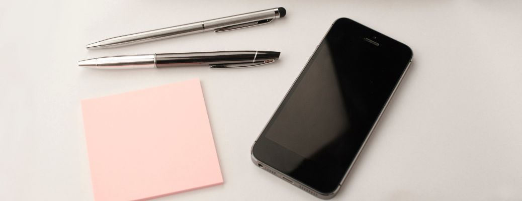 A phone, pen, and sticky notes on a table