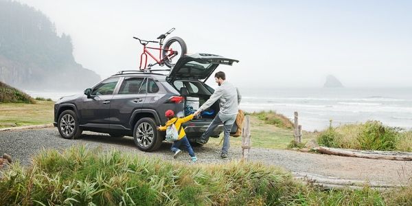 Father and Son in Driveway with Gray 2020 Toyota RAV4 by the Coast