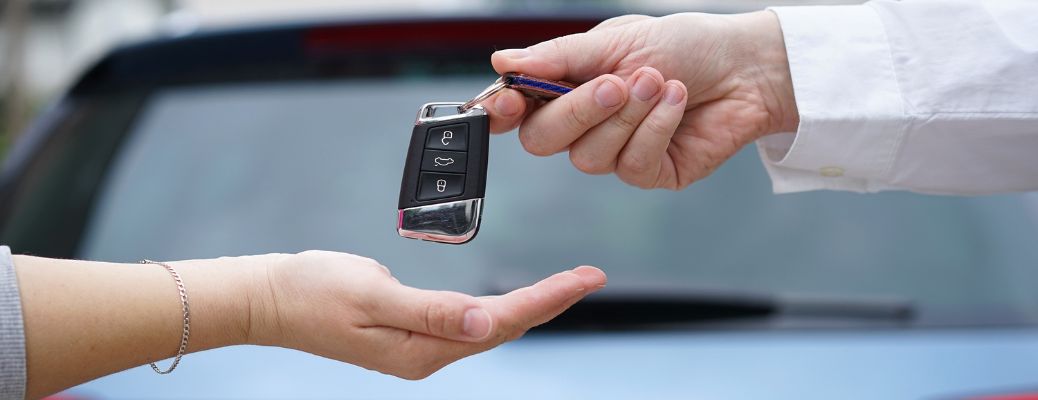 Salesperson giving car key to the customer