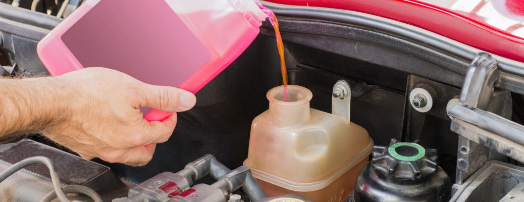 a technician pouring fresh coolant in a car