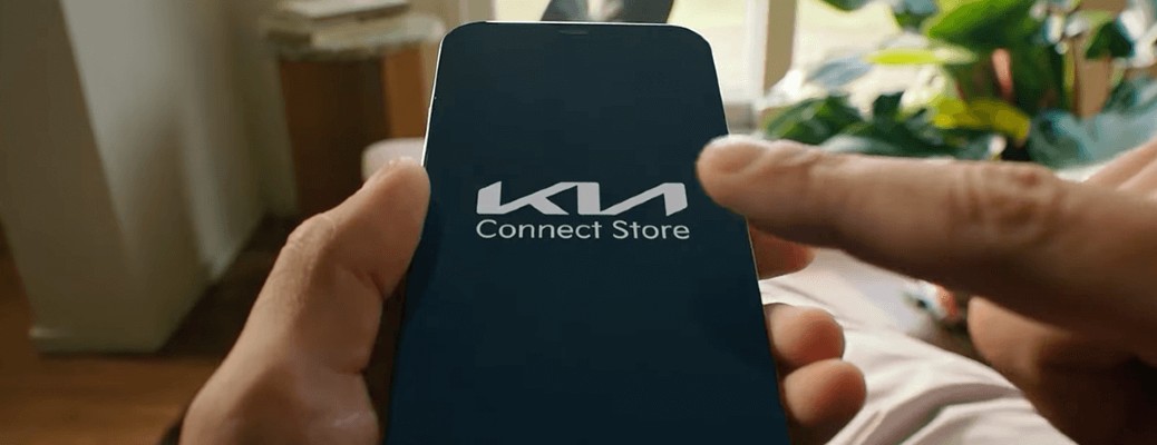 A hand holding a smartphone device with the Kia Connect Store up