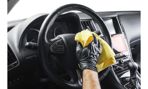a man wiping down a vehicle steering wheel with a yellow cloth