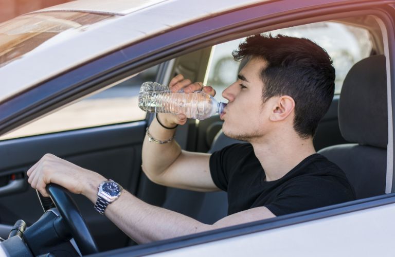 A boy drinking and driving a car