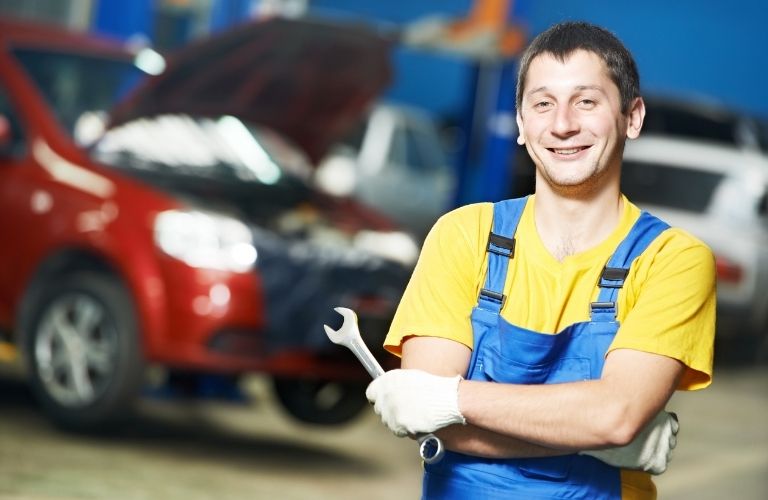 A smiling mechanic posing in front of a tool