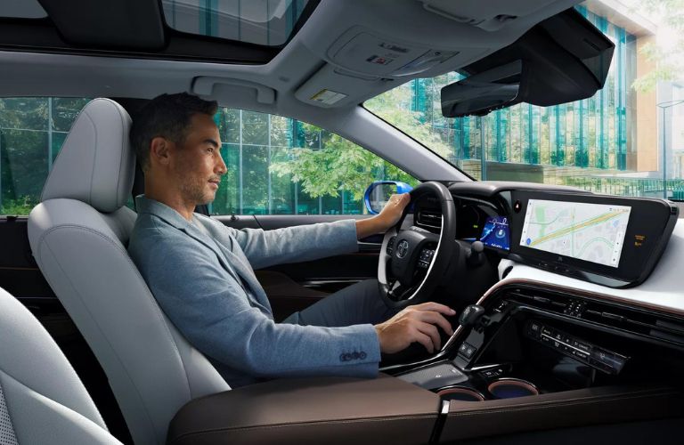 One man in blue shirt is sitting in a car in the driver's seat.