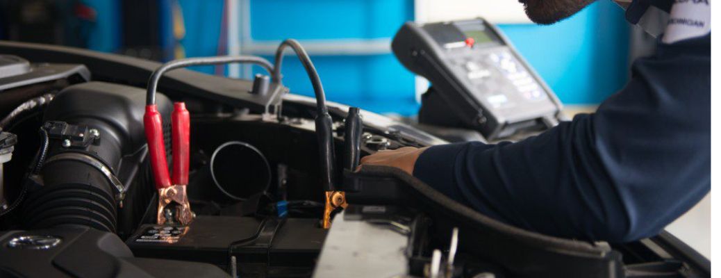 An image of a mechanic inspecting the car battery at the service center.