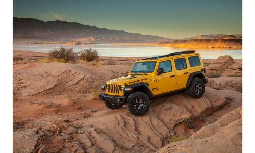 2020 Jeep Wrangler Rubicon EcoDiesel exterior shot with yellow gold paint color parked on a desert rock plain near a lake and mountains