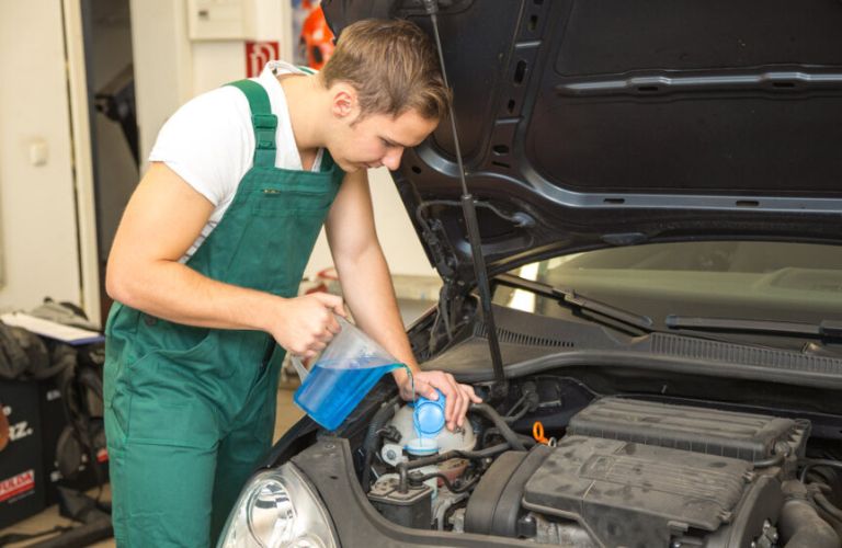 A technician pouring coolant into a car's radiator