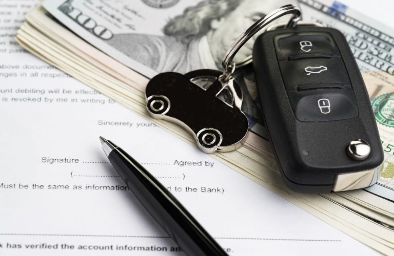 pen, keys, and money on a car loan application