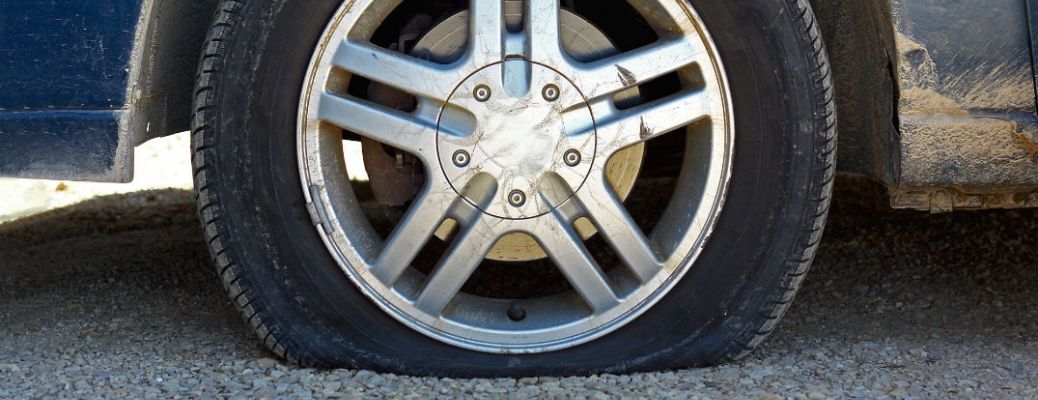 A close-up of a flat tire on a gravel road