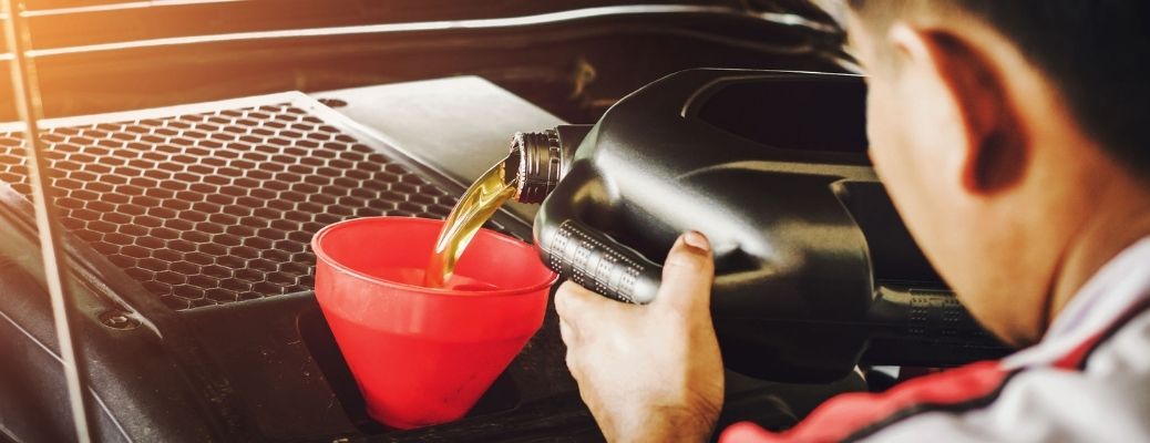 A mechanic pouring oil into a funnel